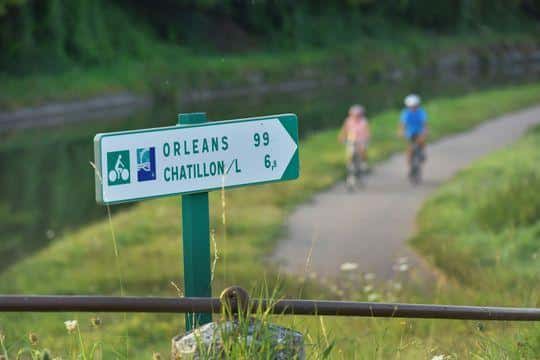Cyclotouristes et panneau de La Loire à vélo près de l'écluse du canal latéral à la Loire, à Beaulieu-sur-Loire